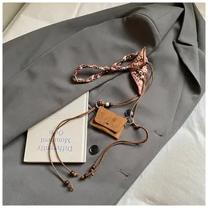 Detail view of a retro brown suede mini coin purse with a patterned silk strap