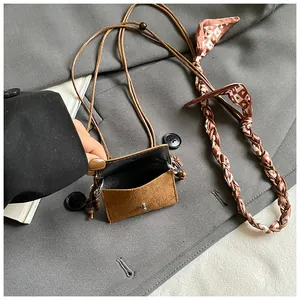 Macro detail of vintage brown suede mini coin purse with decorative scarf strap