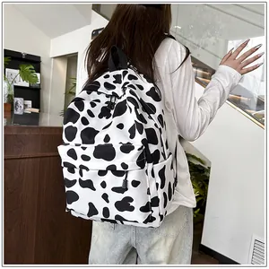 Back view of a stylish black and white cow print backpack worn by a model in a modern setting
