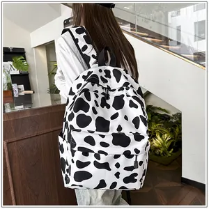 Detail shot of a stylish black and white cow print school backpack worn by a student