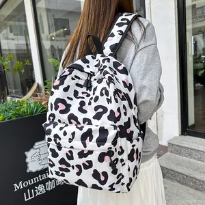 Stylish white leopard print backpack with pink accents for students in a street setting.