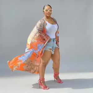 Woman wearing long bohemian orange floral print kimono cardigan with casual denim shorts