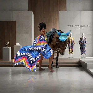 Woman wearing a colorful printed kimono cover-up on a sunny beach next to a horse.