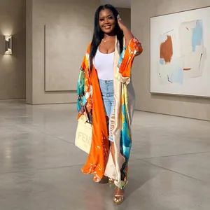 Full length view of a vibrant orange printed satin kimono cardigan on a model outdoors