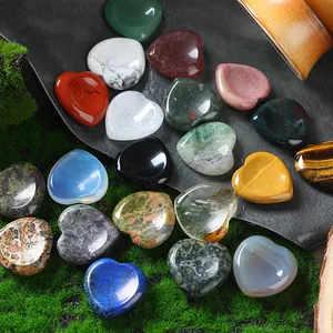 Assorted 30mm heart-shaped natural crystal and agate worry stones displayed on green moss