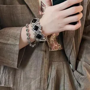 Close-up of vintage black rose and square stone bracelets on a woman's wrist