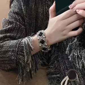 Close-up of a vintage black rose clasp bracelet worn on a wrist with a tweed jacket