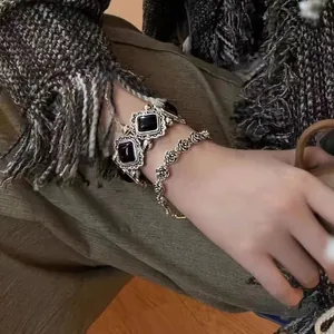 Detailed view of vintage silver rose chain and square black gemstone bracelet on a wrist