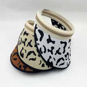 Close-up detail of three knitted leopard print sun visors in white, beige and brown colors