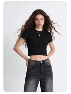 Close-up of a model wearing a slim-fit black short sleeve crop top with grey jeans