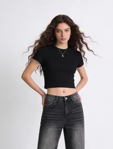 Gros plan d'un mannequin portant un crop top noir ajusté à manches courtes et un jean gris