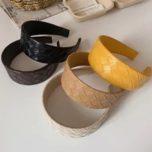 A collection of braided faux leather wide headbands presented in various earthy colors