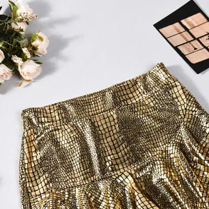 Macro view showing the detailed crocodile texture of a golden metallic faux leather skort