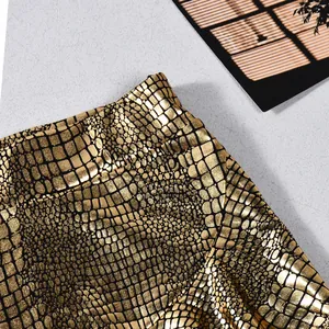 Macro detail shot of golden faux leather skirt-pants with embossed crocodile texture