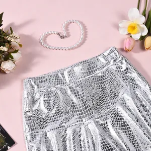 Close-up of silver faux leather skirt with crocodile pattern and metallic finish