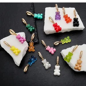 Colorful gummy bear charms with sparkling gold CZ bails displayed on white stones