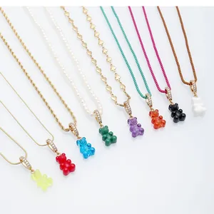 Detailed view of colorful resin gummy bear pendant necklaces on a white background