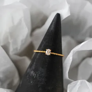 18K gold plated stainless steel twisted band ring with an oval cubic zirconia.