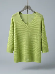 Detail view showing the textured mesh knit pattern of this bright green V-neck sweater