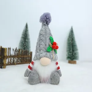 Close-up of a handmade Christmas faceless gnome with a knitted hat and holly decoration