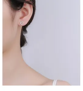 Close-up of hollow heart stud earring with cubic zirconia on model's ear