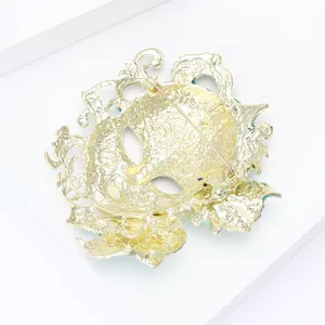 Detailed back view of golden carnival mask brooch showing alloy texture and pin fastener