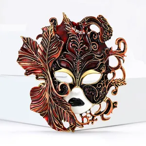 Detailed view of ornate red enamel carnival mask brooch with gold filigree accents