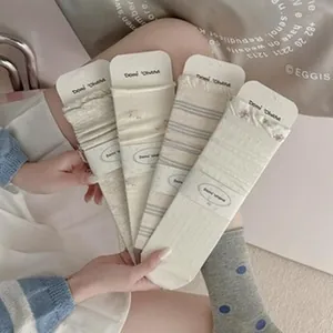 Close-up of four assorted cream-colored cotton mid-calf socks with different patterns