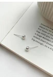 Detailed macro view of minimalist S999 sterling silver glossy round bead bean stud earrings