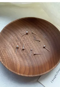 Macro view of various sized S999 sterling silver ball stud earrings on a wood plate.