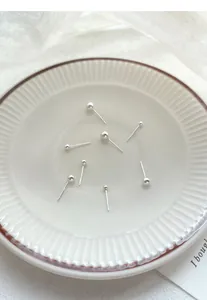 Close-up of S999 sterling silver ball stud earrings on a white ceramic plate
