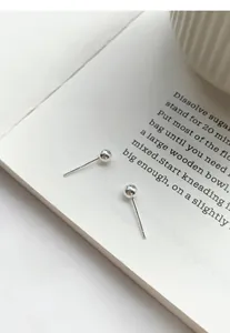 Minimalist S999 sterling silver round bead stud earrings shown on an open book page