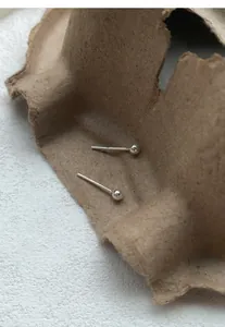 Close-up of S999 sterling silver ball stud earrings on rustic paper background
