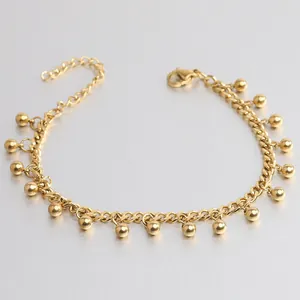 Primo piano dettagliato di un braccialetto minimalista in acciaio con perline oro.