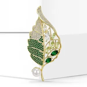 Detailed view of an elegant gold leaf brooch featuring green zirconia and a white pearl.