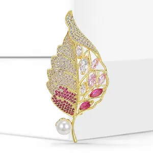 Detailed view of an elegant gold-toned leaf brooch with micro-paved zircons and pearl