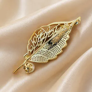 Elegant golden leaf-shaped brooch with pearl detail featured on smooth silk fabric