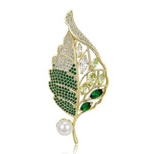 Elegant gold-tone leaf brooch with shimmering green zircons and a white pearl accent charm