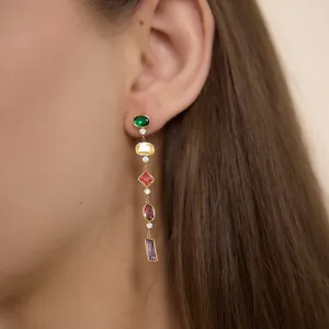 Close-up of a colorful geometric gemstone tassel earring worn on an ear showing fine details.