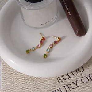 Detailed view of colorful zircon tassel earrings on a white ceramic tray