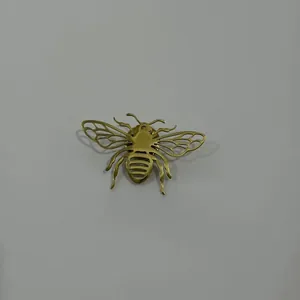 Détail macro d'une broche abeille en acier inoxydable doré aux ailes évidées