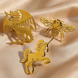 Detailed view of gold stainless steel animal brooch pins: dragon, bee, and unicorn.