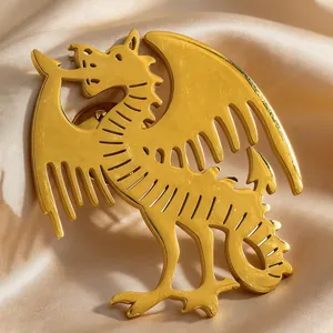Detailed macro view of a golden dragon-shaped brooch pinned on champagne silk fabric