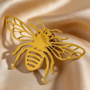 Detailed macro view of a luxurious golden bee-shaped stainless steel brooch on satin