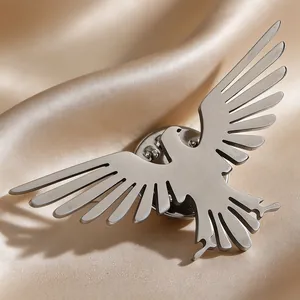 Macro view of a polished stainless steel bird brooch presented on elegant silk fabric