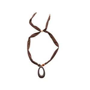 Ethnic style necklace with printed fabric ribbon, wooden beads, and dark brown oval pendant.