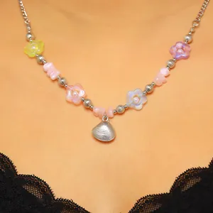 Collana bohémien con ciondolo a conchiglia, fiori colorati e perle rosa indossata