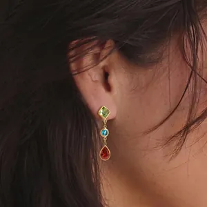 Close-up of geometric stainless steel earrings with colorful zircon stones on model ear