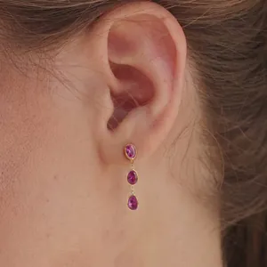 Macro shot of elegant gold stainless steel drop earrings with pink oval stones.
