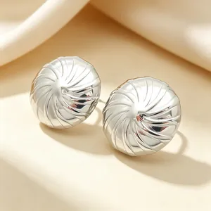 Nahaufnahme von silberfarbenen Edelstahl-Ohrsteckern mit spiralförmiger Struktur.